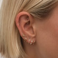 a woman wearing gold ear cuffs with small diamonds on the end of her ears and behind her ear is a pair of earrings