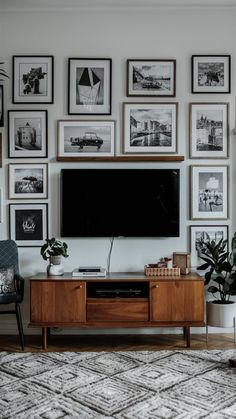 a living room with pictures on the wall and a television in the center, along with a rug