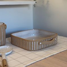 two ceramic dishes on a table with spoons and utensils next to them