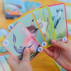 a person holding four cards in front of a table full of children's books