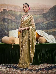 This chic tissue sari is an exquisite embodiment of timeless elegance, featuring delicate dabka work and a gotta patti border adorned with ghumroos. Paired with a chanderi silk blouse embellished with intricate mirror work, this ensemble blends traditional craftsmanship with a modern flair, perfect for elevating your festive look. Eid Traditional Wear With Gota Work On Tissue Silk, Transitional Tissue Silk Pre-draped Saree, Diwali Tissue Silk Sharara With Gota Work, Designer Silk Pre-draped Saree With Mirror Work, Eid Chanderi Pre-draped Saree With Traditional Drape, Eid Chanderi Pre-draped Saree, Eid Tissue Silk Saree In Traditional Drape, Eid Tissue Silk Pre-draped Saree In Traditional Drape, Tissue Silk Pre-draped Saree For Eid