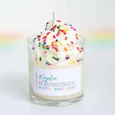 a birthday candle with sprinkles in a glass container on a white background