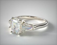 a three stone engagement ring with baguettes on the sides and side stones in white gold