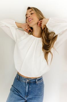 a woman with her arms behind her head and hands on her hips, posing for the camera