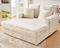 a large white couch sitting on top of a rug in a living room next to a window