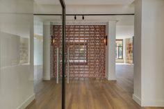 an empty room with wood flooring and glass partitions on the wall to divide it from the rest of the room