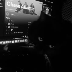 a black cat sitting in front of a monitor with the word chase atlantic on it