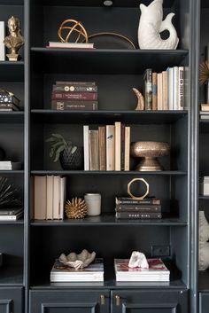 a bookshelf filled with lots of books next to a vase and other items