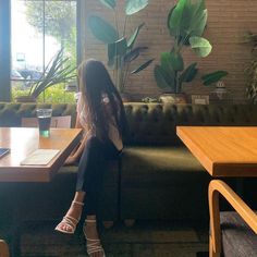 a woman sitting on top of a green couch next to a table with a cup