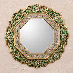 a green and gold mirror with flowers on the border, in front of a white background