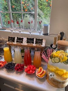 a table filled with fruit and drinks on top of a counter next to a window