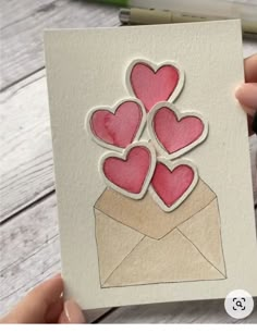 someone holding up a card with hearts in an envelope