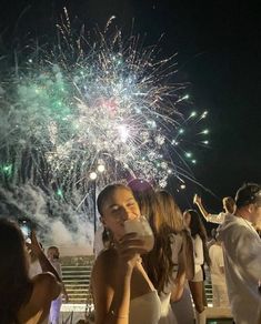 a group of people standing next to each other with fireworks in the sky