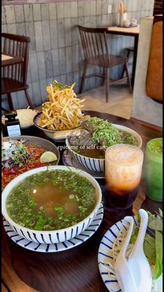 a table topped with bowls of food and plates of fries next to each other on top of a wooden table