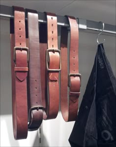 leather belts hanging from hooks in a closet