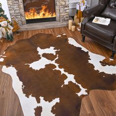 a brown and white cowhide rug in front of a fireplace