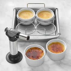 four cups are sitting in front of a toaster with sauces on the bottom