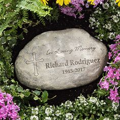 a memorial stone surrounded by flowers and greenery