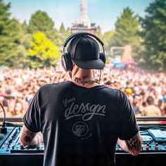 a man with headphones on standing in front of a dj's booth at a music festival