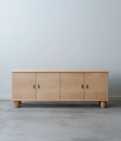 a wooden cabinet sitting on top of a cement floor next to a wall with two doors