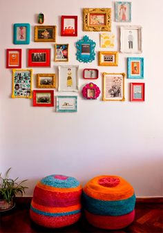 two colorful ottomans sitting next to each other in front of a wall with pictures on it