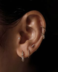 a woman's ear with three different piercings on her left side and two smaller ones in the middle