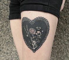 a woman's thigh with a heart shaped piece of lace and flowers on it