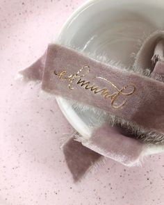 a white bowl with a pink and gold name on it