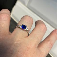 a person's hand with a ring on it and a blue stone in the middle