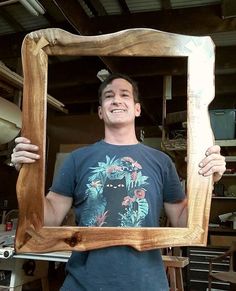 a man is holding up a wooden frame