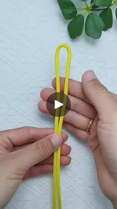 two hands holding a yellow string with a ring on it and another person's hand next to the string