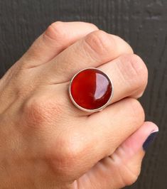 A stunning blood red and orange hued carnelian has been set in sterling silver with a handmade ring band from sterling silver half dome wire. This red carnelian has different hues throughout with varying colors of brighter red to darker red. The stone is 18mm in size. Made to order! Carnelian is a stabilizing stone and helps clear negative energy as well as stimulate creativity! Polished Carnelian Orange Jewelry, Orange Polished Carnelian Jewelry, Red Carnelian Jewelry With Cabochon, Luxury Red Carnelian Jewelry With Cabochon, Red Sterling Silver Ring With Natural Stones, Red Sterling Silver Rings With Natural Stones, Red Carnelian Cabochon Ruby Ring, Carnelian Cabochon Ruby Ring, Red Carnelian Ring With Polished Finish