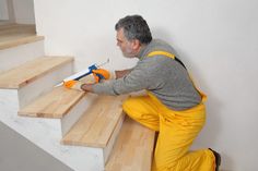 a man in yellow pants and overalls is painting the stairs with a paint roller