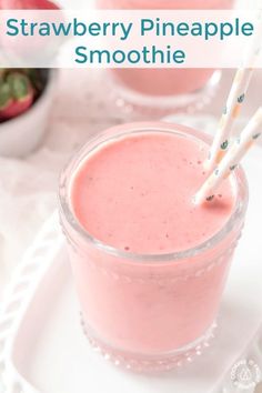 two glasses filled with pink smoothie on top of a white plate next to strawberries