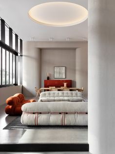 a large bed sitting in the middle of a room next to two orange bean bags