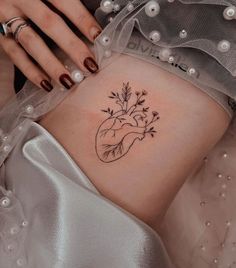 a woman's stomach with a small heart tattoo on her left side ribcage