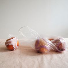 two bagels wrapped in plastic sitting on top of a bed next to each other