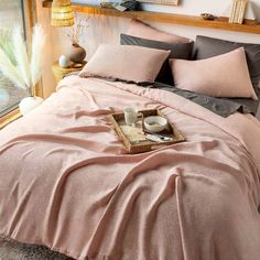 a bed covered in pink sheets and pillows