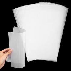 a hand is holding several sheets of white paper