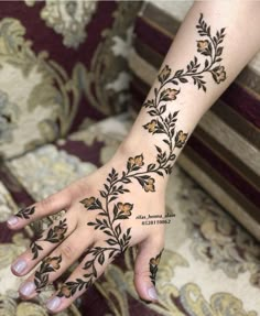 a woman's hand with hennap and flowers on her left arm, in front of a couch