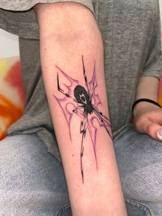 a person with a spider tattoo on their arm sitting down and looking at the camera