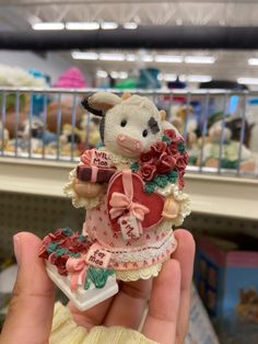 a hand holding a small figurine in the shape of a cow wearing a dress