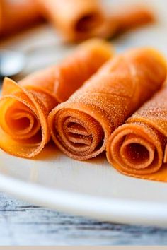 three rolled up carrots sitting on top of a white plate