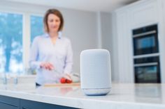 a woman standing in a kitchen next to an amazon smart speaker on a counter top