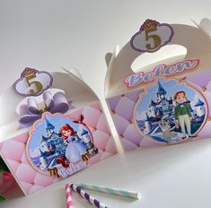 two princess themed birthday boxes with candy and straws next to them on a table