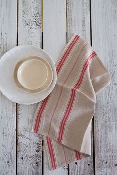 a white plate with a red stripe on it next to a napkin and a cup