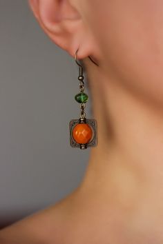 Beautiful and unique boho earrings with orange czech glass faceted 10 mm, green irregular shape glass beads, antique brass  square charms and antique brass earring hooks. Earring hooks are from nickel free and lead free metal. Unique jewelry for your boho outfit or a great gift for someone special! *The total lenght of earrings is about 49 mm including earring hooks. Other earrings of my shop you can see here: https://www.etsy.com/shop/NaTavelli?section_id=13757927  Thanks for visit. Bohemian Orange Drop Earrings, Bohemian Orange Earrings, Bohemian Orange Beaded Earrings For Gifts, Orange Bohemian Drop Earrings Jewelry, Bohemian Orange Czech Glass Earrings, Orange Bohemian Drop Earrings, Vintage Orange Earrings With Czech Glass, Orange Beaded Drop Earrings For Pierced Ears, Vintage Orange Czech Glass Earrings