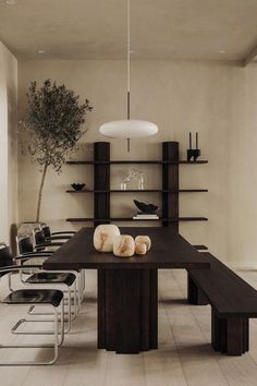 a dining room table with chairs and a potted tree in the corner on one side