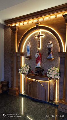 an altar with flowers and statues on it in a room that is lit up at night