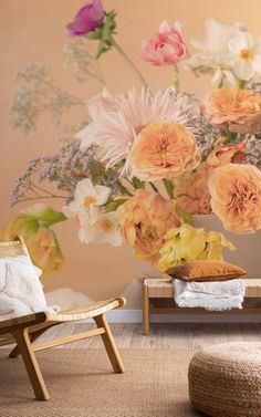 an arrangement of flowers in a vase on a table next to a chair and ottoman